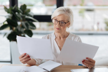 An older woman comparing two documents.